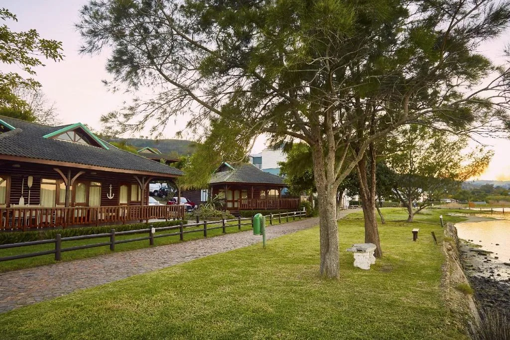 Rustic wooden lodge buildings with manicured gardens and mature trees