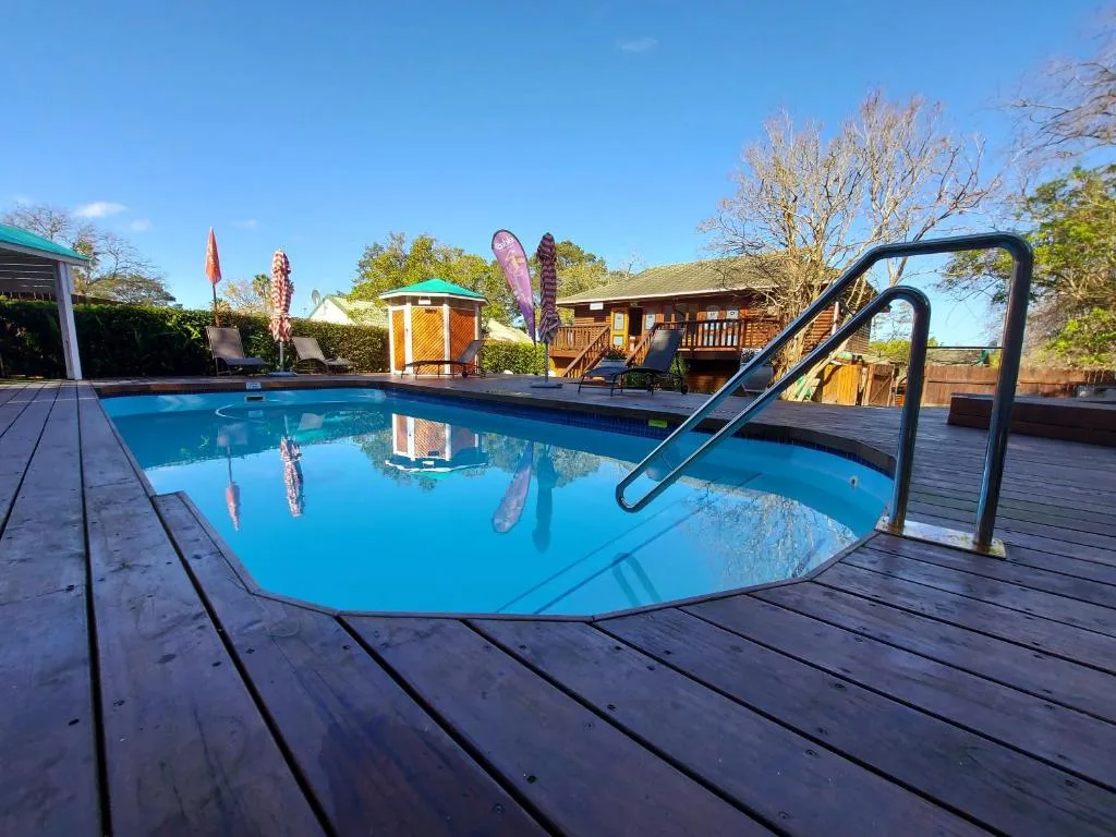 Sparkling blue swimming pool with metal railing and wooden deck surrounding property