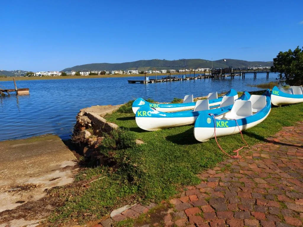 Scenic waterfront view with blue boats, lagoon, and mountains beyond