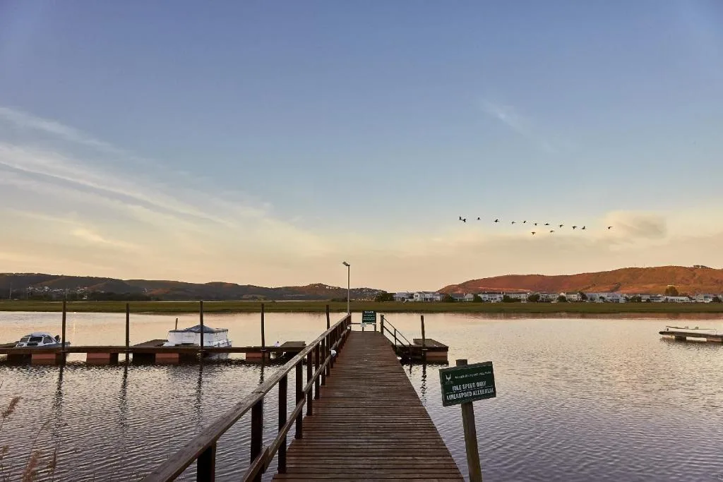 Scenic lagoon view with wooden jetty, moored boats, and distant hills