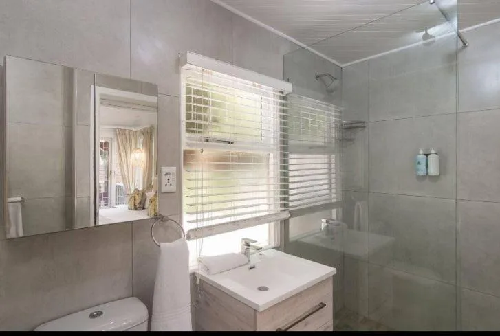 Modern bathroom with vanity, mirror, shower enclosure, and window blinds