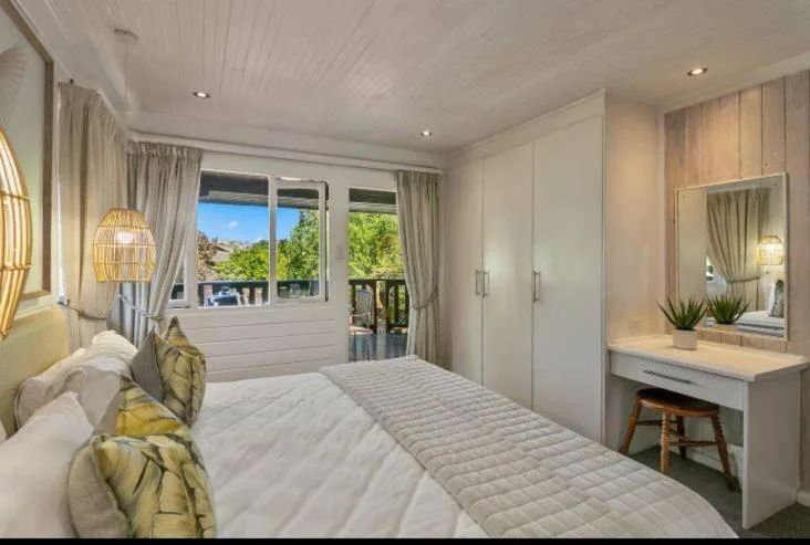Bright bedroom with queen bed, ensuite vanity, and outdoor deck access