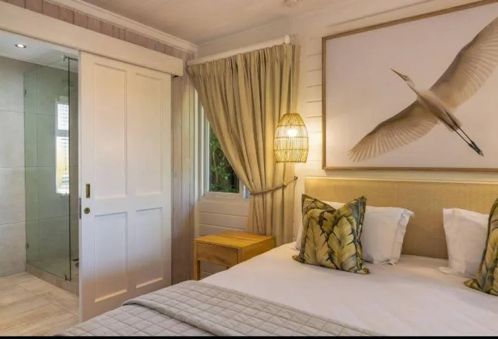 Bright bedroom with king bed, gold headboard, ensuite bathroom visible