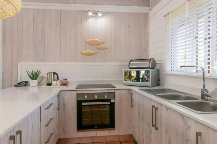 Modern kitchen with light wood cabinetry, stainless steel appliances, white countertops
