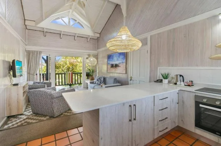 Open-plan lounge and kitchen with vaulted ceiling and deck access