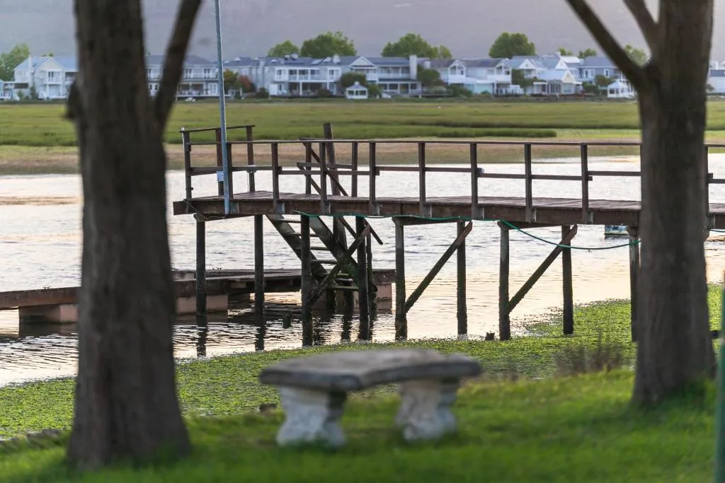 Waterfront view with wooden jetty, lagoon, and residential homes beyond