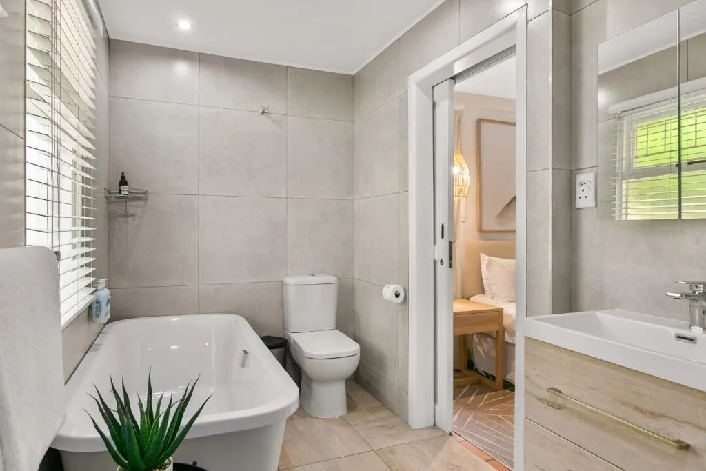 Modern bathroom with freestanding tub, toilet, and vanity mirror