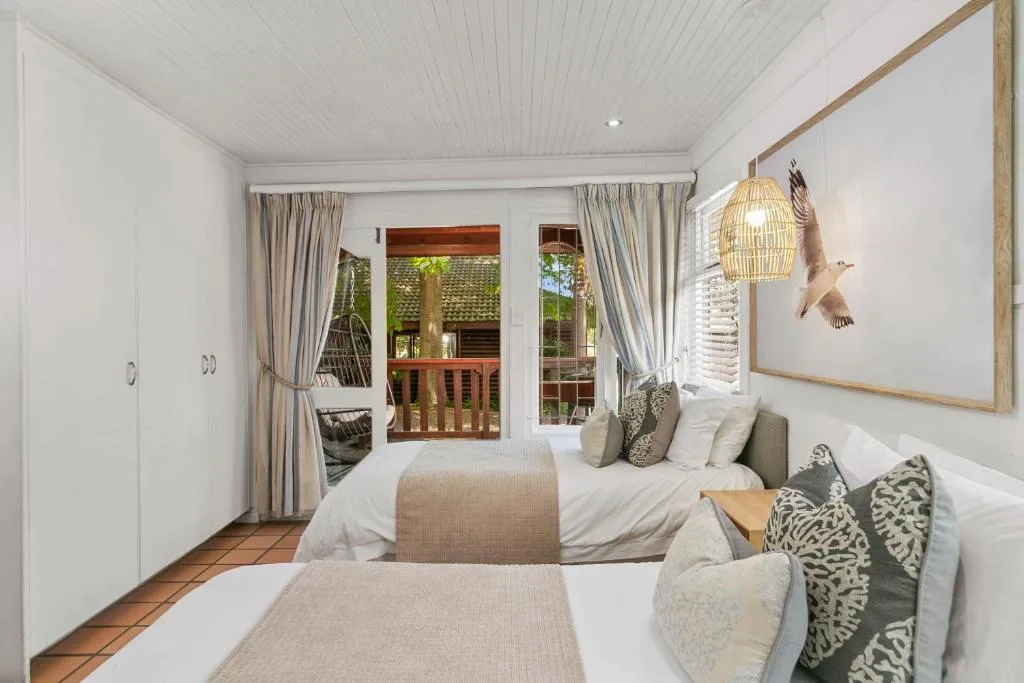 Bright bedroom with twin beds, deck access, and coastal decor accents