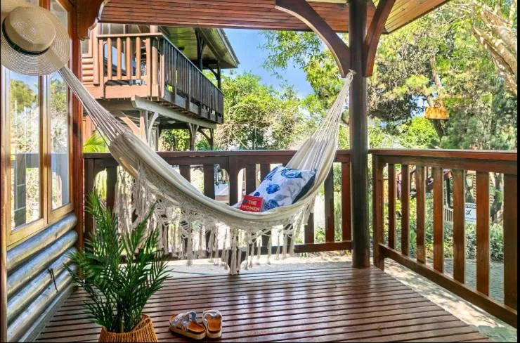 Wooden deck with hammock, potted plants, and forest views surrounding the cottage