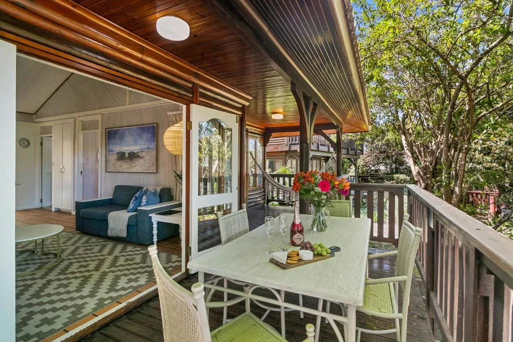 Covered deck with dining table, chairs, flowers, and forest views