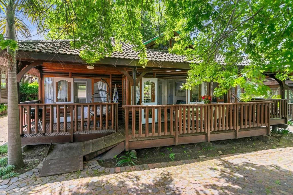Charming cottage with wooden deck, green awning, brick pathway entrance
