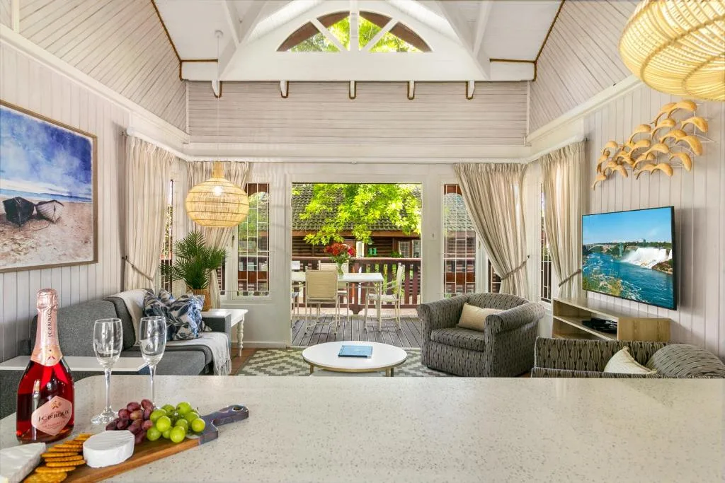 Bright open-plan lounge with sofas, TV, and deck access beyond
