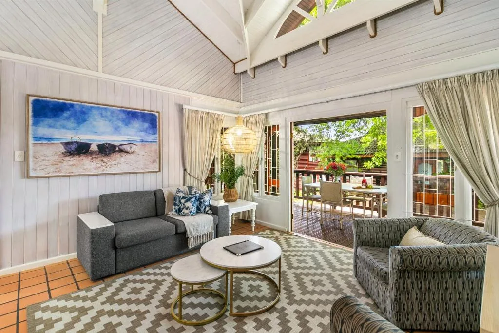 Bright modern lounge with gray sofa, patterned armchairs, and ocean artwork