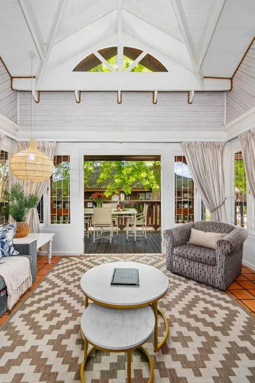 Bright open-plan lounge with vaulted ceiling and garden views through doors