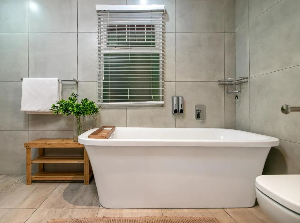 Modern bathroom with freestanding white soaking tub and wooden storage bench
