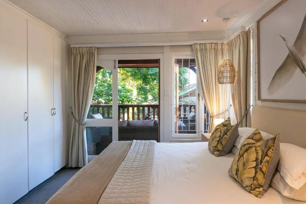 Bright bedroom with queen bed, deck access, and green forest views
