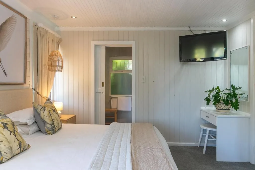 Bright bedroom with white walls, double bed, and wall-mounted TV