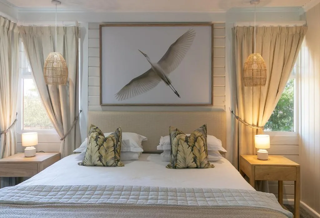Bright bedroom with queen bed, woven pendant lights, and bird artwork