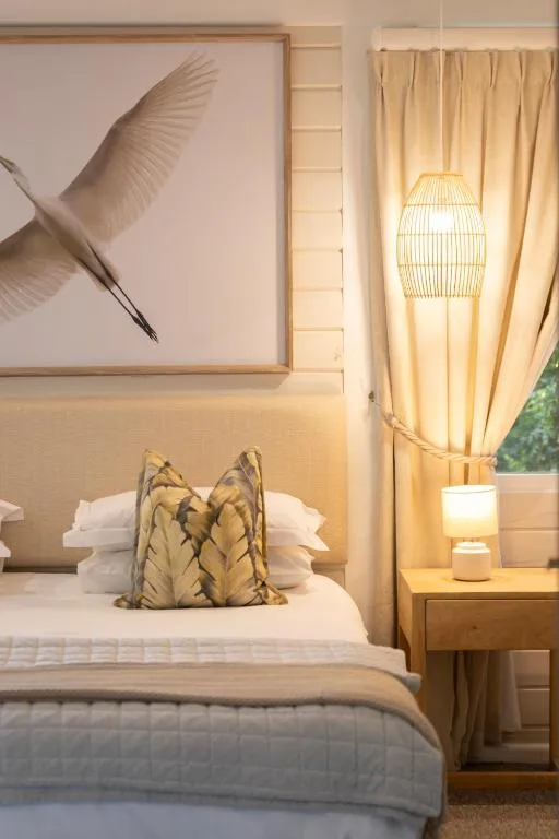 Serene bedroom with neutral tones, framed art, decorative pillow, and warm lighting