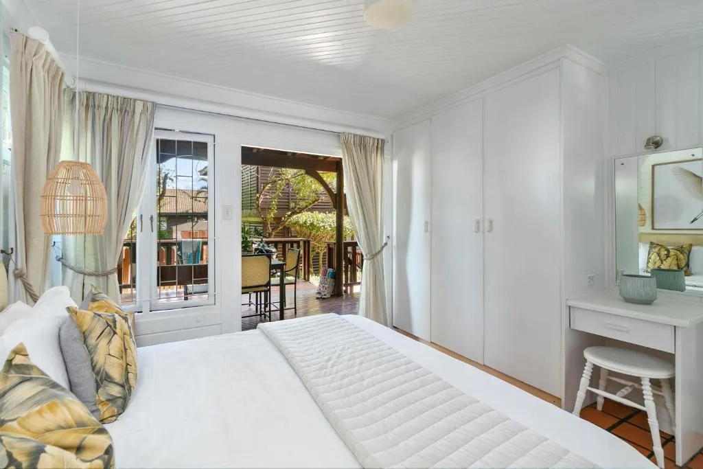 Bright bedroom with queen bed, glass doors opening to deck with ocean views