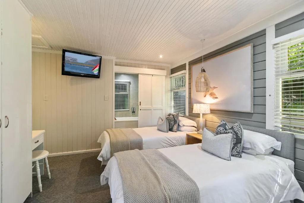 Modern bedroom with two beds, TV, and contemporary furnishings and lighting