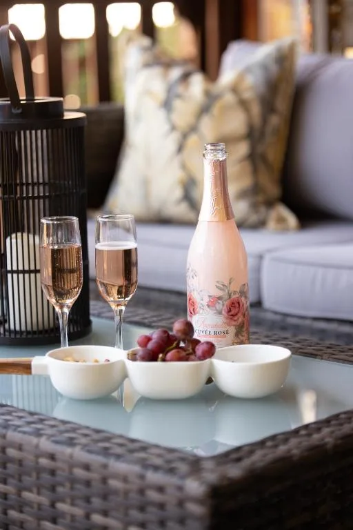 Outdoor seating area with champagne, glasses, and fruit on table