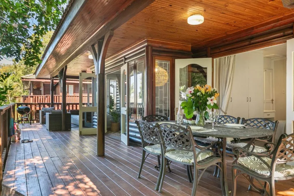 Spacious covered timber deck with dining table and braai area