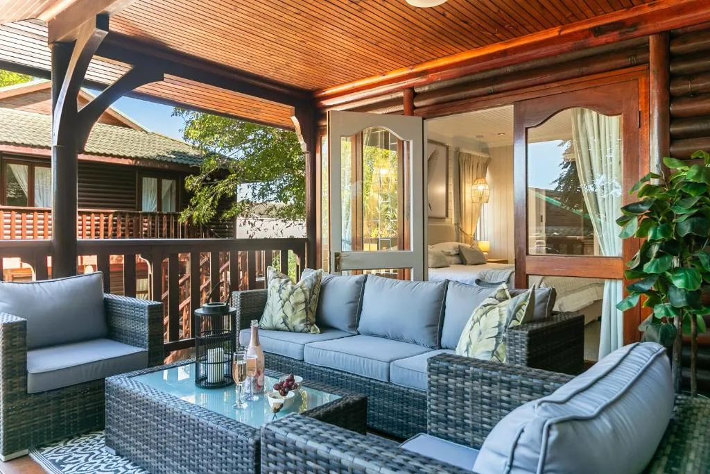Covered outdoor patio with wicker seating and glass doors opening to bedroom
