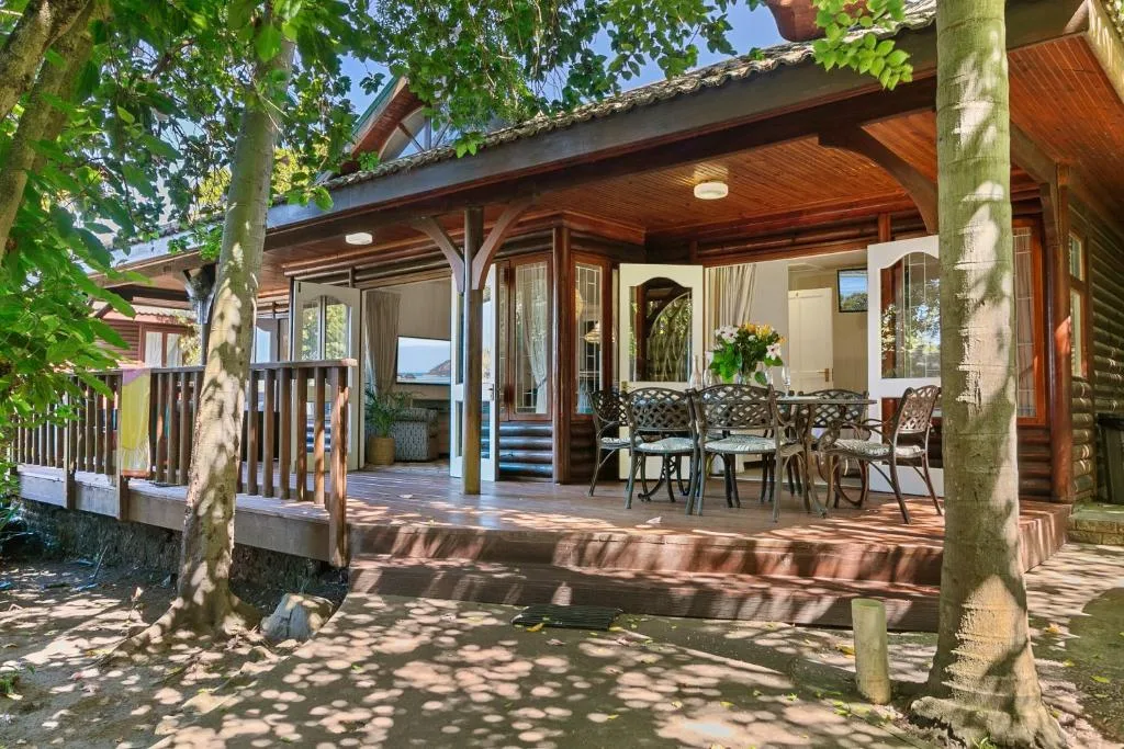 Covered wooden deck with dining table and chairs, garden views
