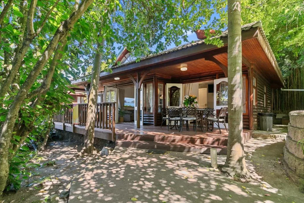 Shaded wooden deck with seating area beneath mature trees