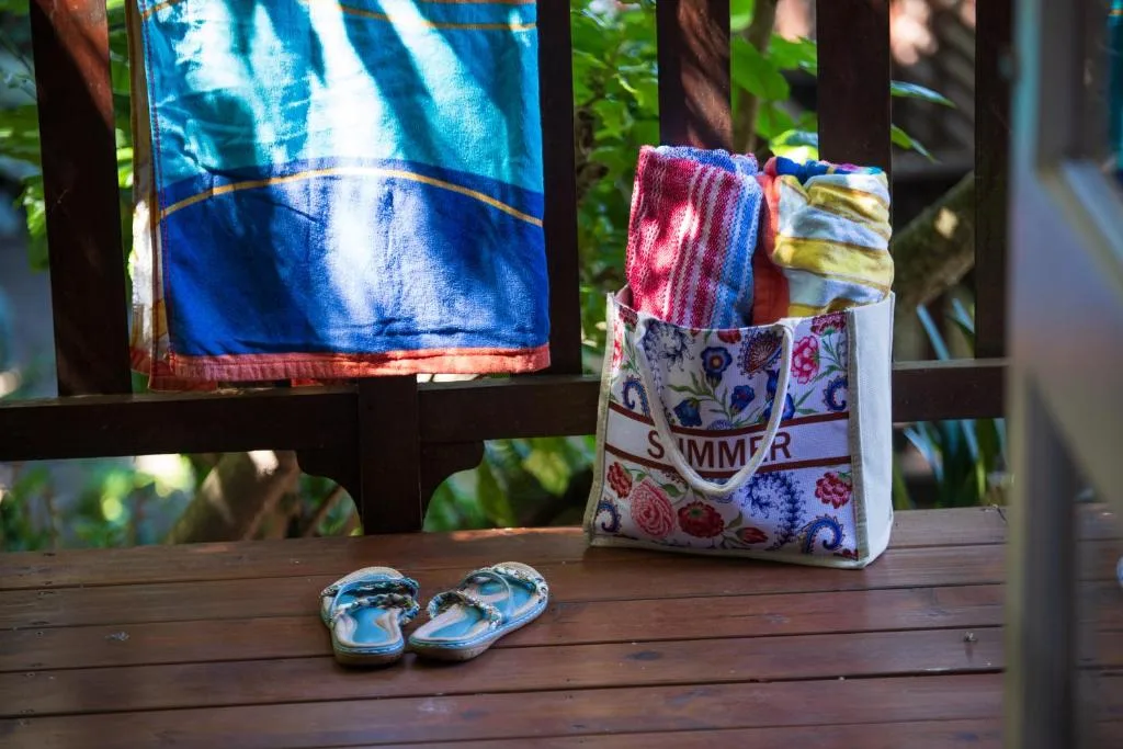 Colorful towels and flip-flops drying on a sunny wooden deck
