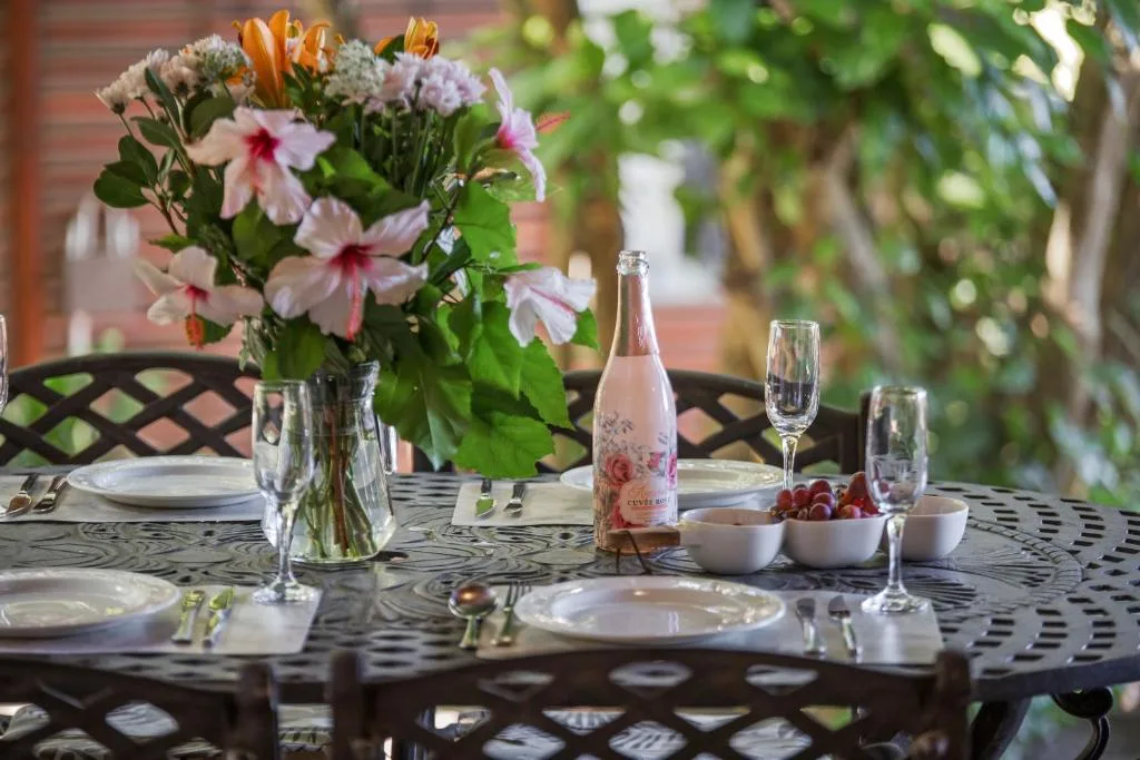 Elegant outdoor dining table set with flowers, wine, and place settings