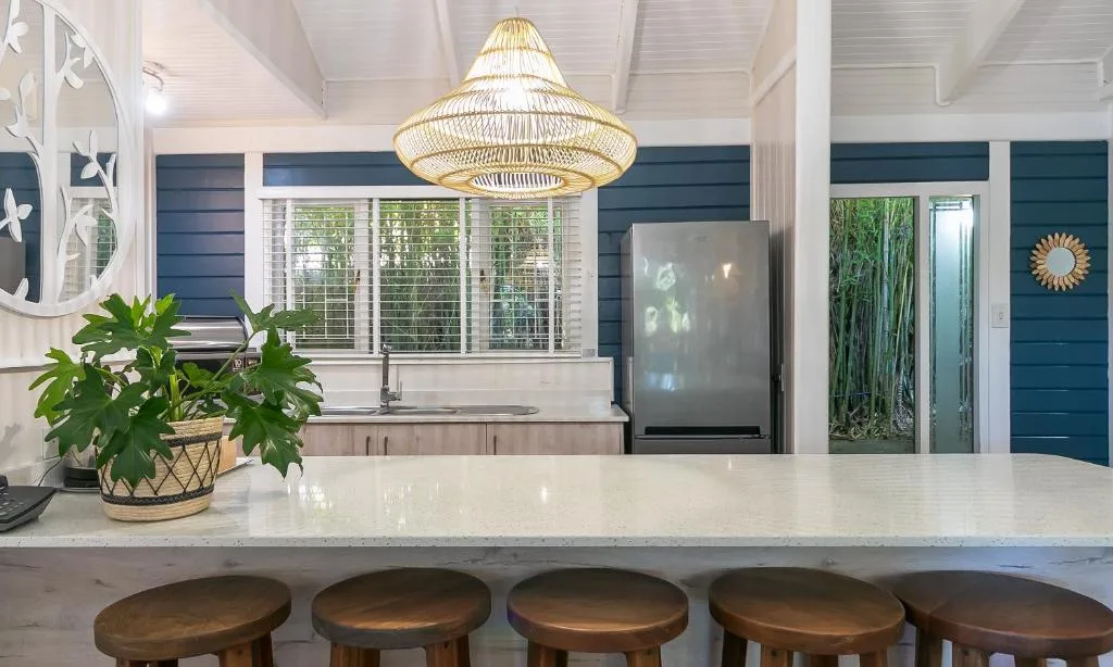 Modern kitchen with white counters, dark cabinetry, and woven pendant light