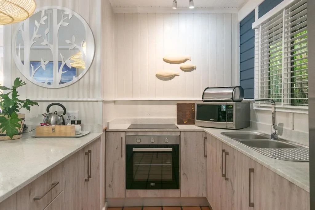 Modern kitchen with light wood cabinetry, stainless steel appliances, and white countertops