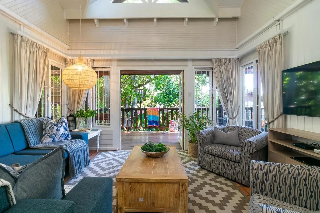 Bright living room with blue sofa, deck views, woven pendant light, and TV