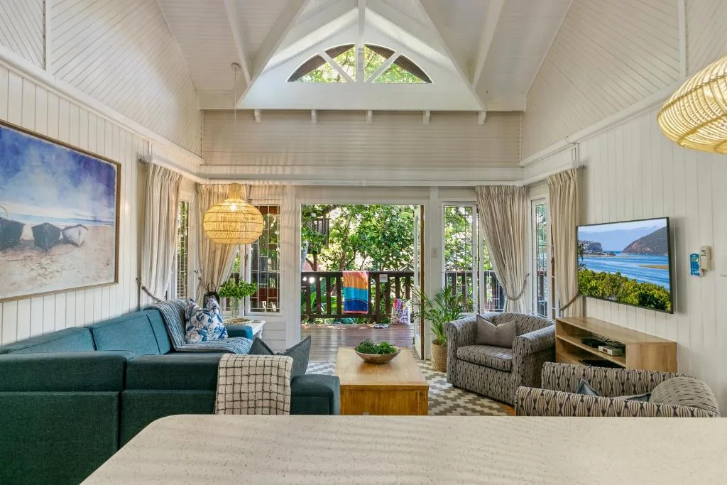 Bright lounge with vaulted ceiling, green sofa, and views to deck