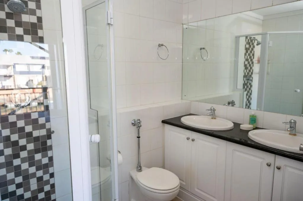Modern bathroom with dual vanity, black countertop, and walk-in shower enclosure