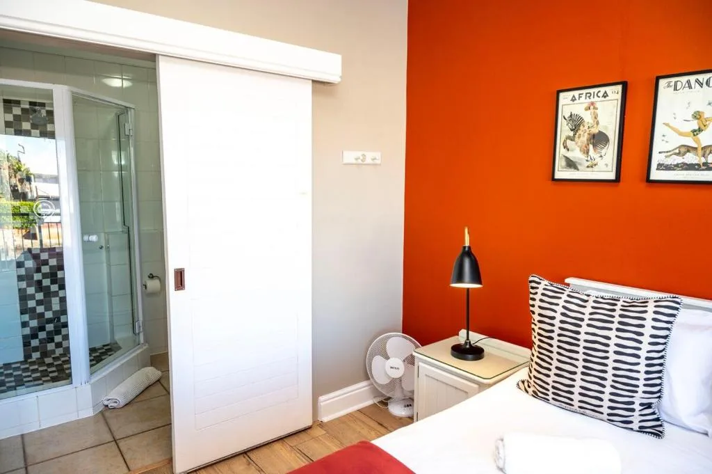 Bright bedroom with orange accent wall, patterned pillow, and en-suite bathroom