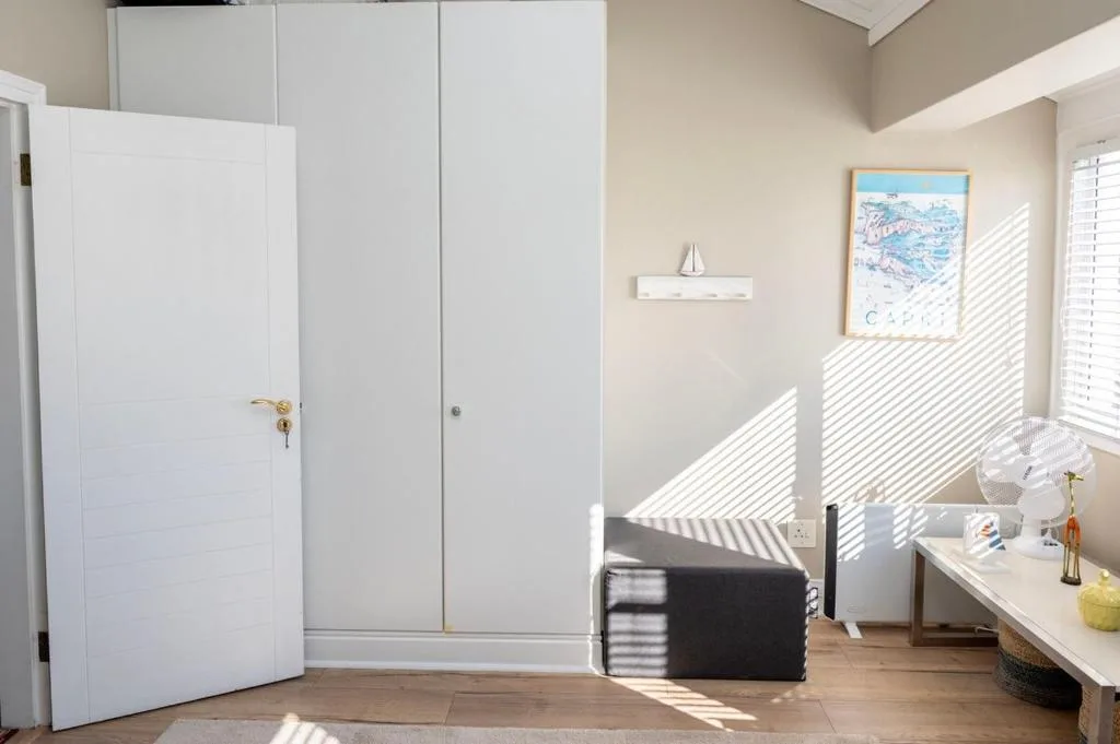 Bright bedroom with white built-in wardrobes and natural light from windows