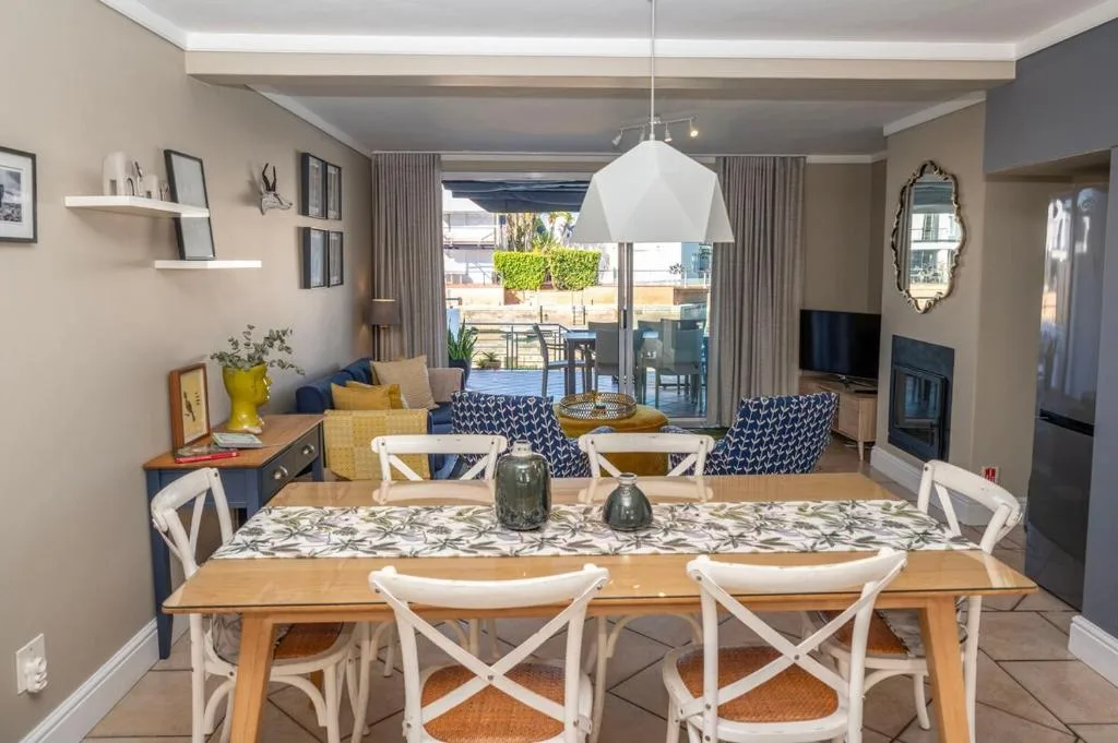 Modern dining area with wooden table and white chairs overlooking lagoon