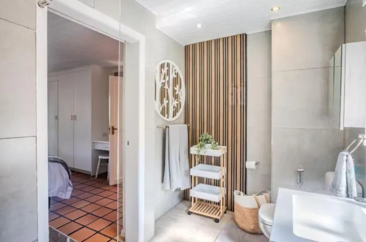 Modern bathroom with white vanity, toilet, and striped accent wall decor