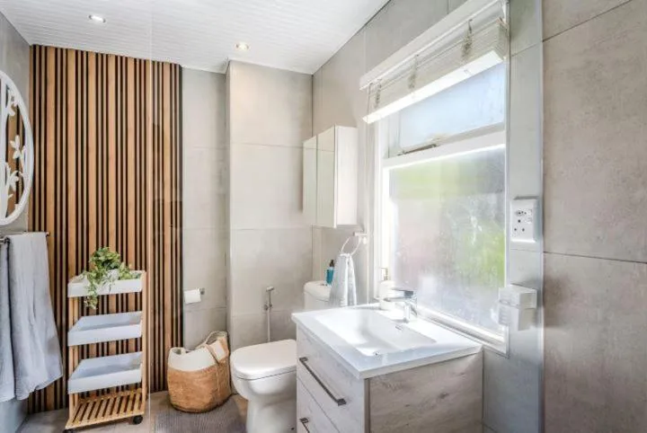 Modern bathroom with vanity sink, toilet, and window overlooking garden
