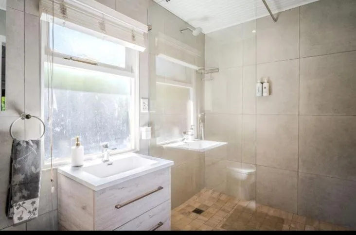 Modern bathroom with white vanity, large window, and glass shower enclosure