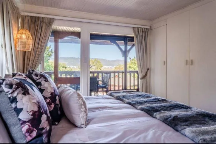 Bright bedroom with double bed, mountain views through glass doors and windows