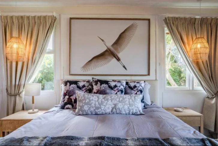 Bright bedroom with bed, artwork, windows, and elegant pendant lighting fixtures