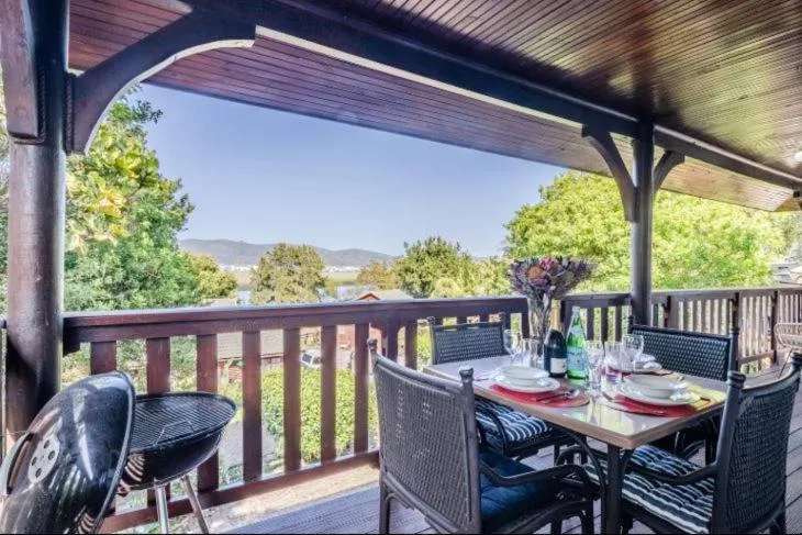 Covered deck with dining table overlooking lush garden and distant mountains
