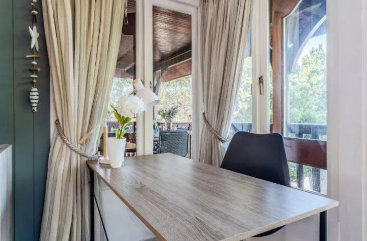 Dining area with wooden table, black chairs, and garden views through windows