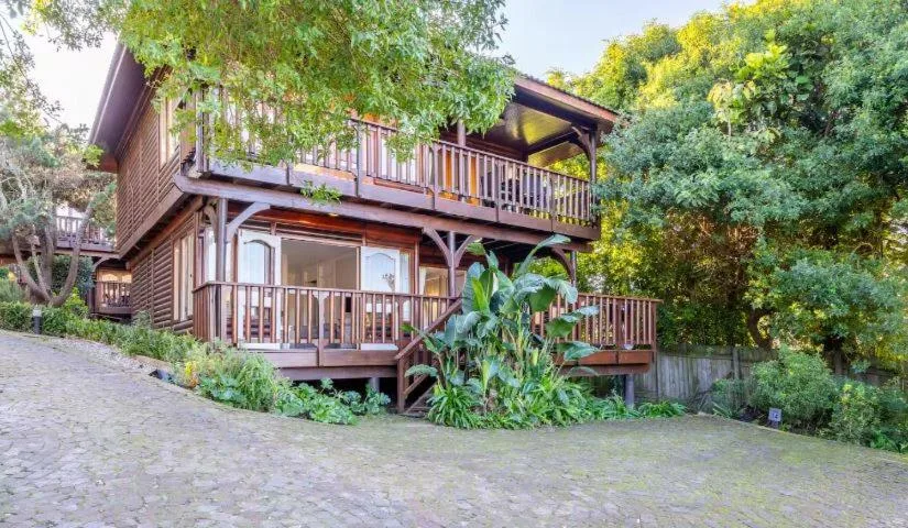 Wooden chalet with multi-level decks nestled among mature trees