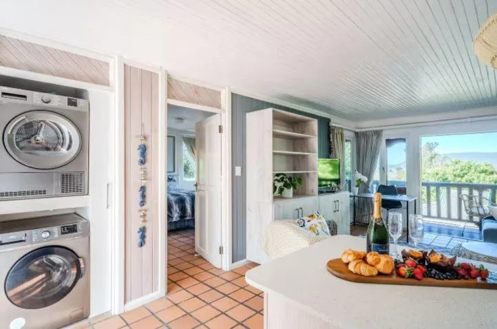 Modern kitchen with stacked laundry appliances, white cabinetry, and scenic water view beyond