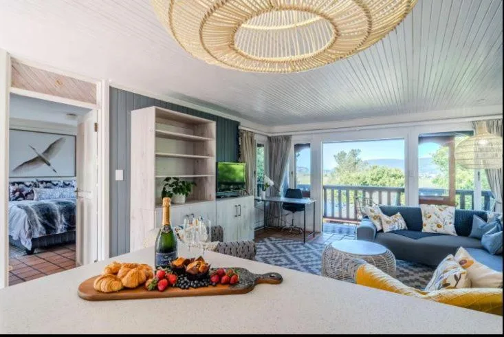Open-plan lounge with sofa, large windows overlooking Knysna lagoon views
